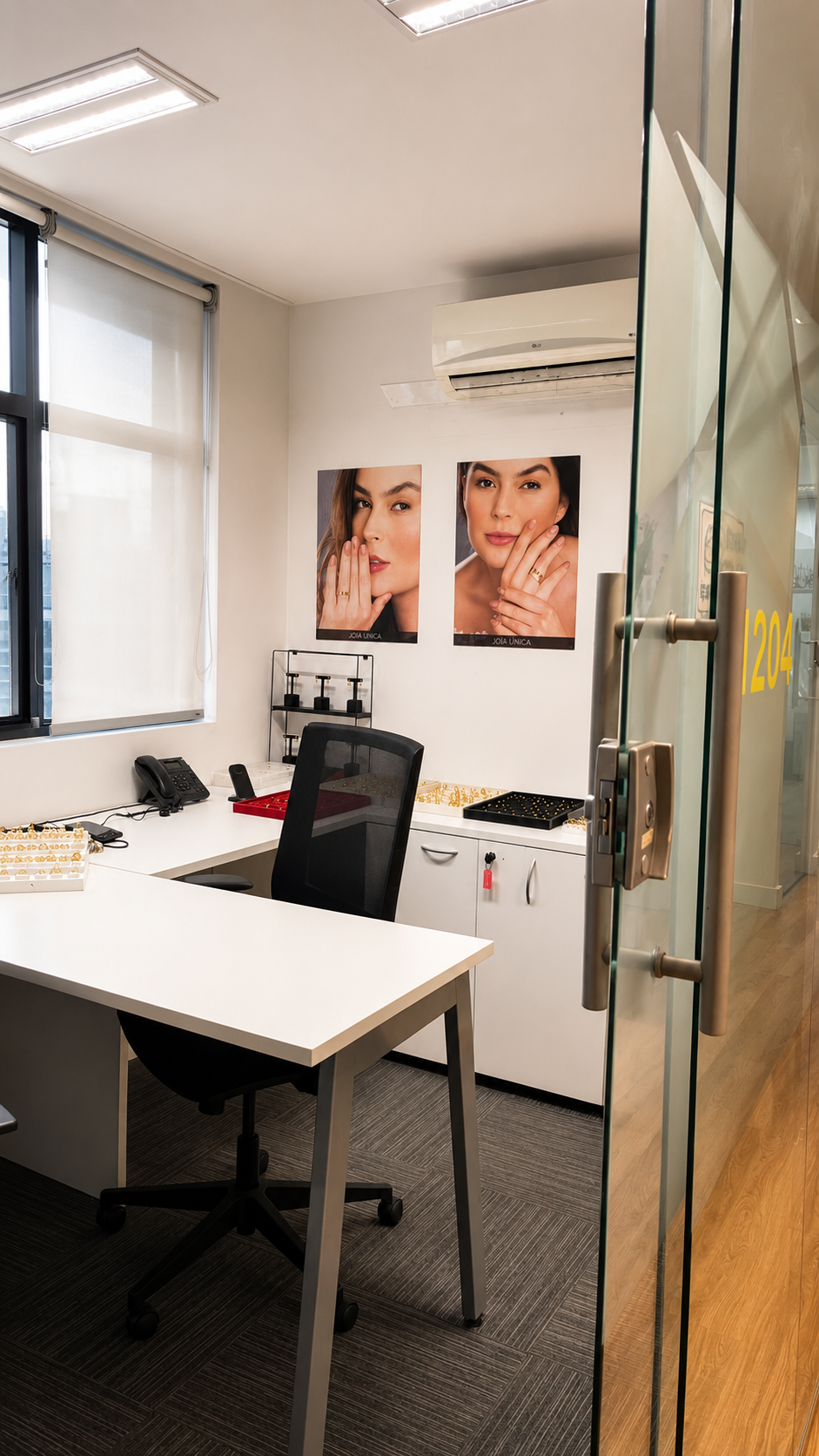 Sala de atendimento do showroom Joia Única com mostruários e porta de vidro